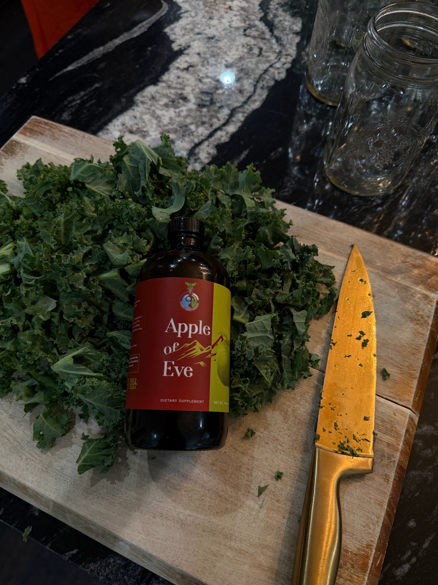 Apple of Eve bottle arranged with kale on a kitchen cutting board